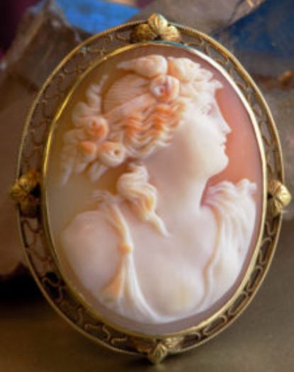 A woman wearing an ornate cameo is shown.