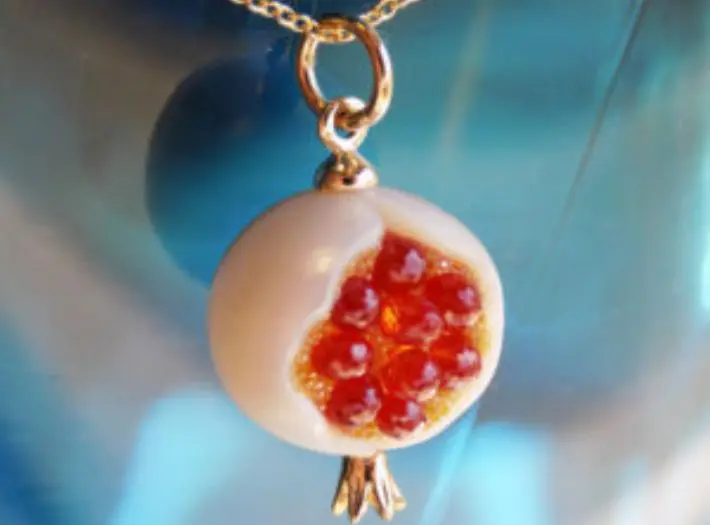 A close up of a necklace with an image of a pomegranate