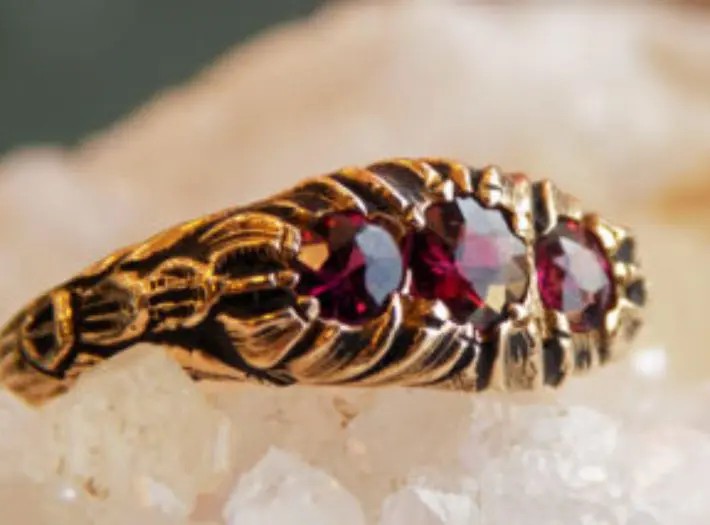 A gold ring with three red stones on it.