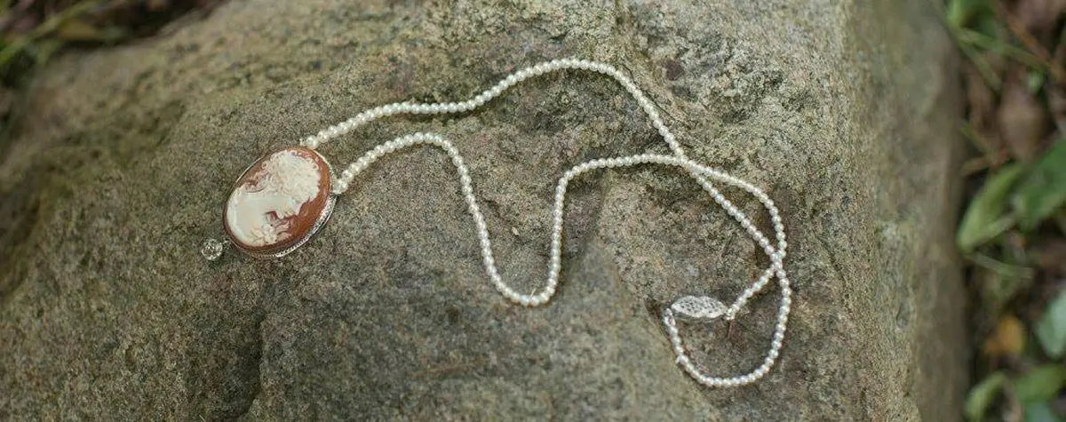 A necklace of pearls and a leaf on the ground.