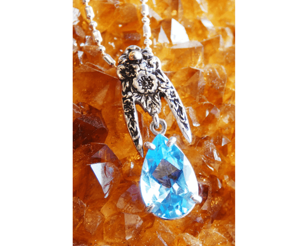 A necklace with an image of a hand and a blue stone.